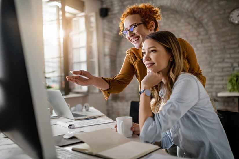 happy female entrepreneurs reading email computer while working together office focus is redhead woman 637285 1967