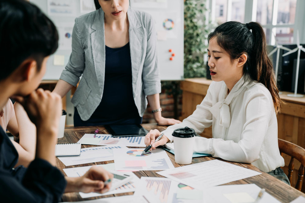 group web designers developing new website layout modern office confident pregnant woman manager standing table board room listening employee asking question creative team workers