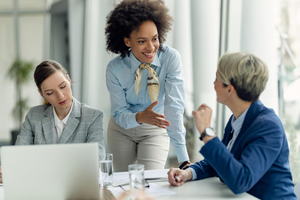 happy african american businesswoman talking female colleagues while working office