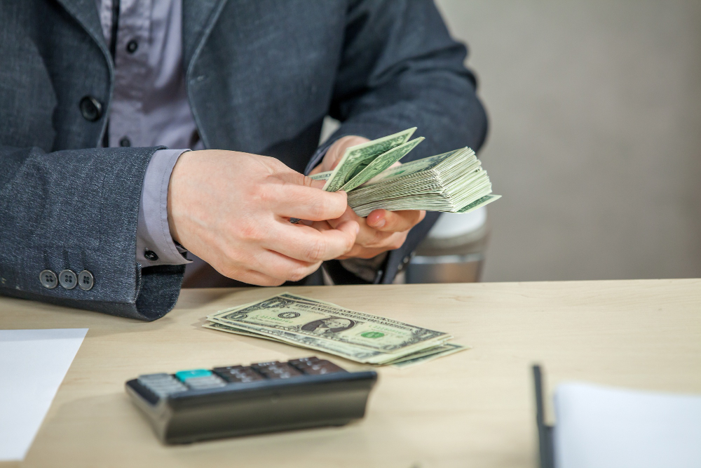 young businessman working from his office counting cash money