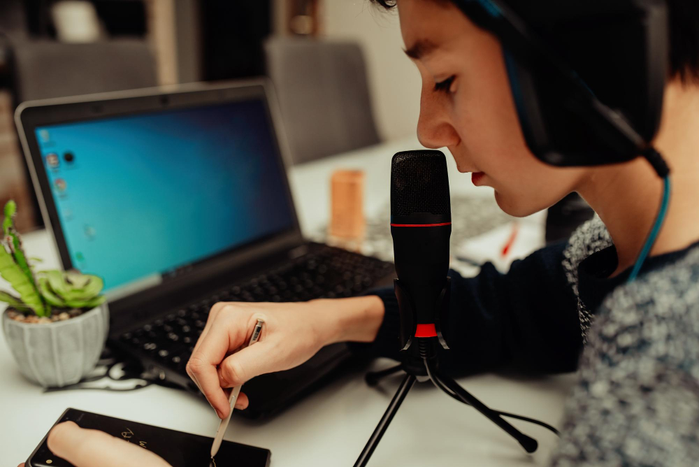 young guy modern headset studies from home using laptop