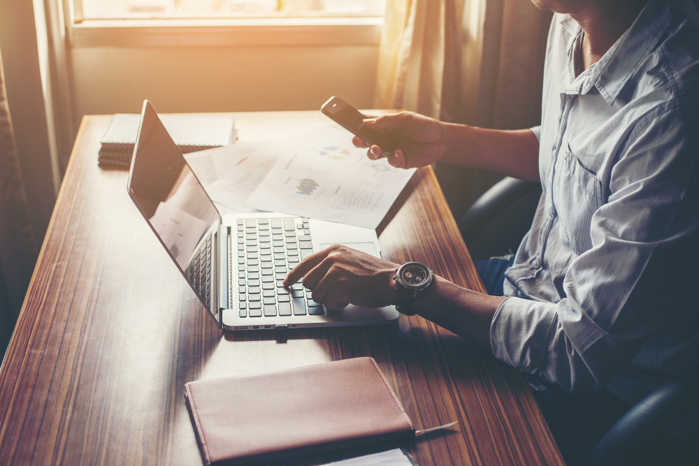 businessman hands using cell phone with laptop office desk