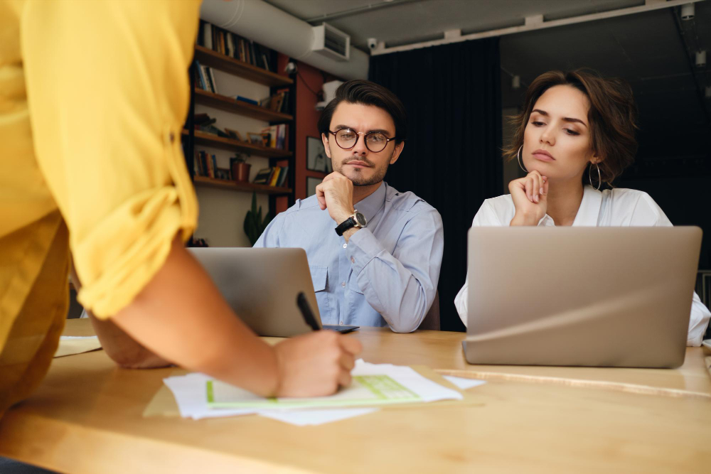 group business colleagues sitting desk with laptop while thoughtfully working with papers modern office